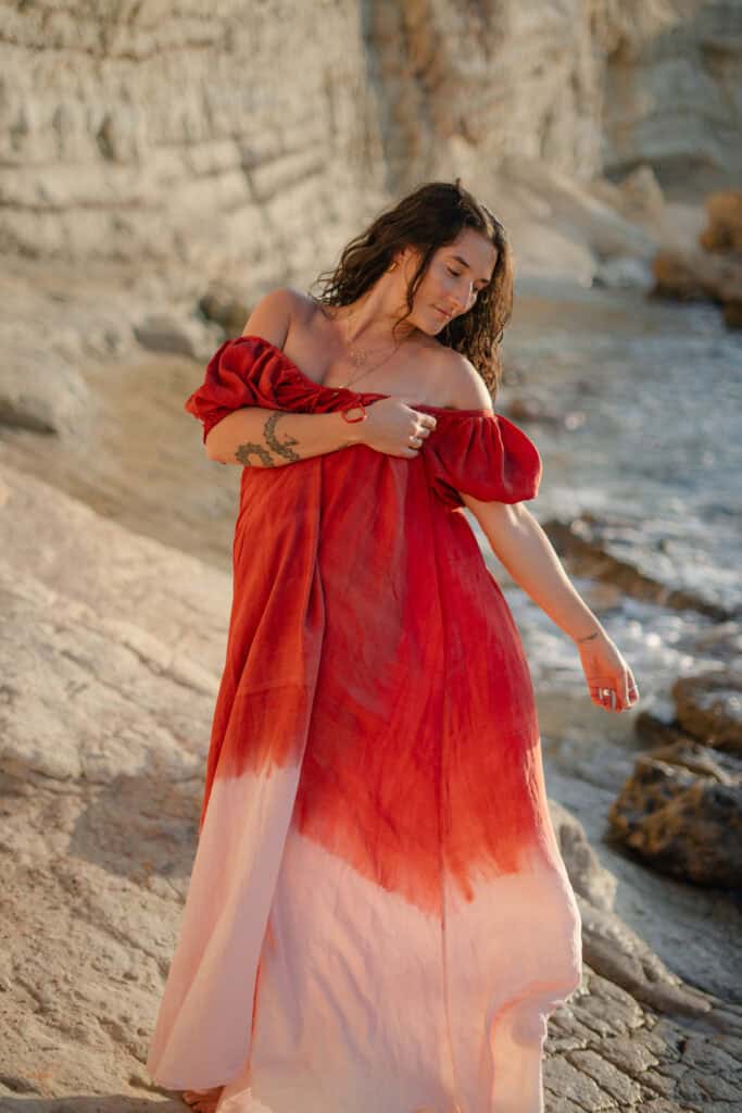 Elegante Frau am Strand in rotem Maxikleid, Naturfotografie für Mode und Lifestyle.