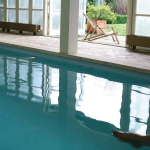 Entspannter Innenpool mit großem Fenster, gemütliche Liegestühle und gepflegte Gartenblick.